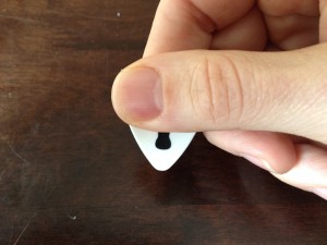 Thumb crosses the back of the pick (at the top). It covers up the majority of the pick. 
