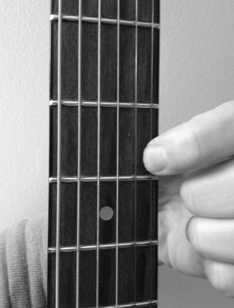 how to press down a string on a guitar